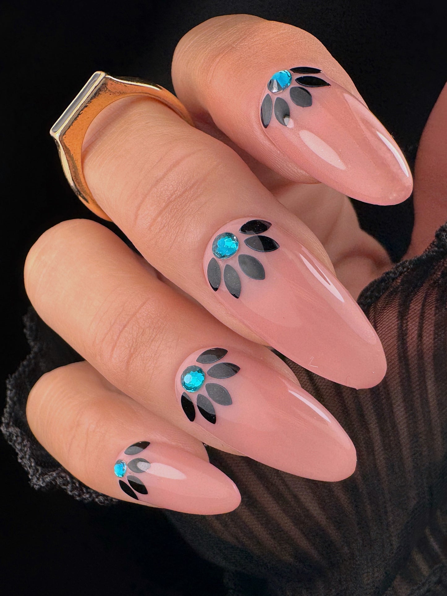 Nails with decorative designs featuring blue and black elements on a dark background