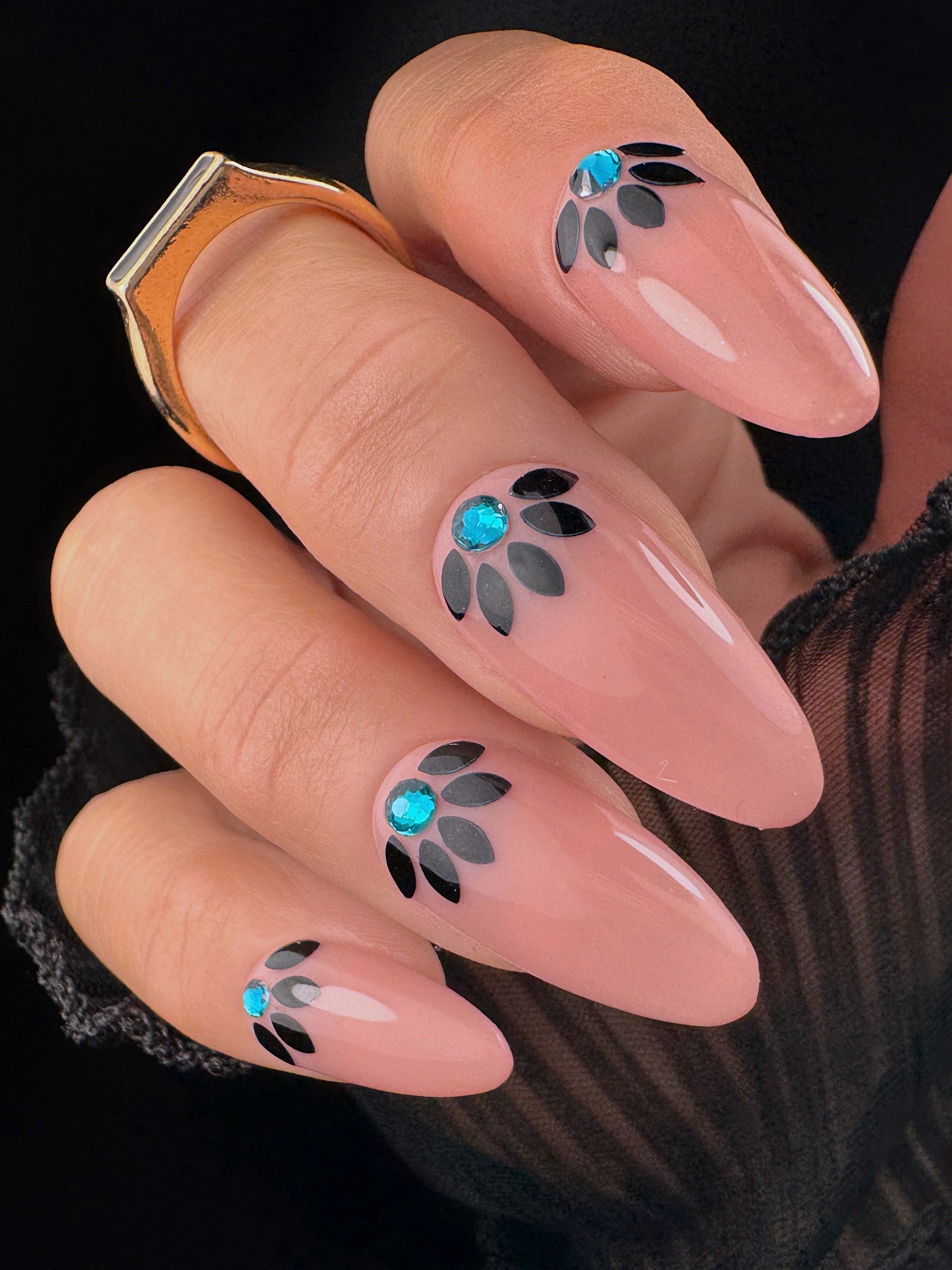 Nails with decorative designs featuring blue and black elements on a dark background