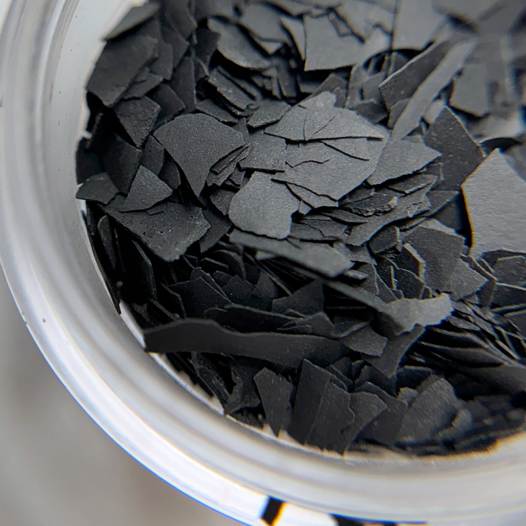 Close up of matte black flakes in clear jar