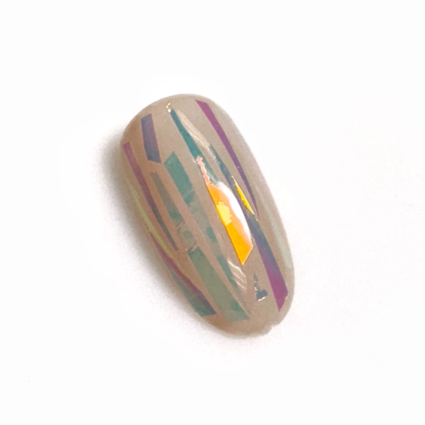 Close up of mylar confetti on neutral nail tip on light background