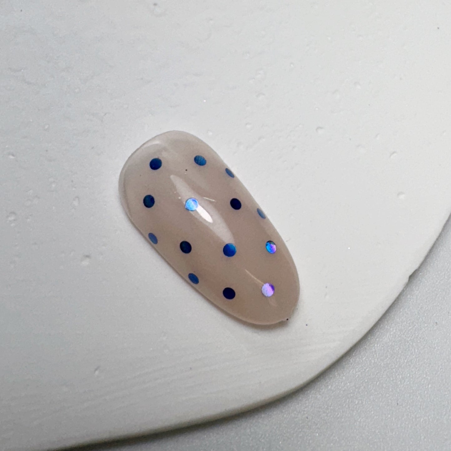 Decorated nail tip on white textured surface.