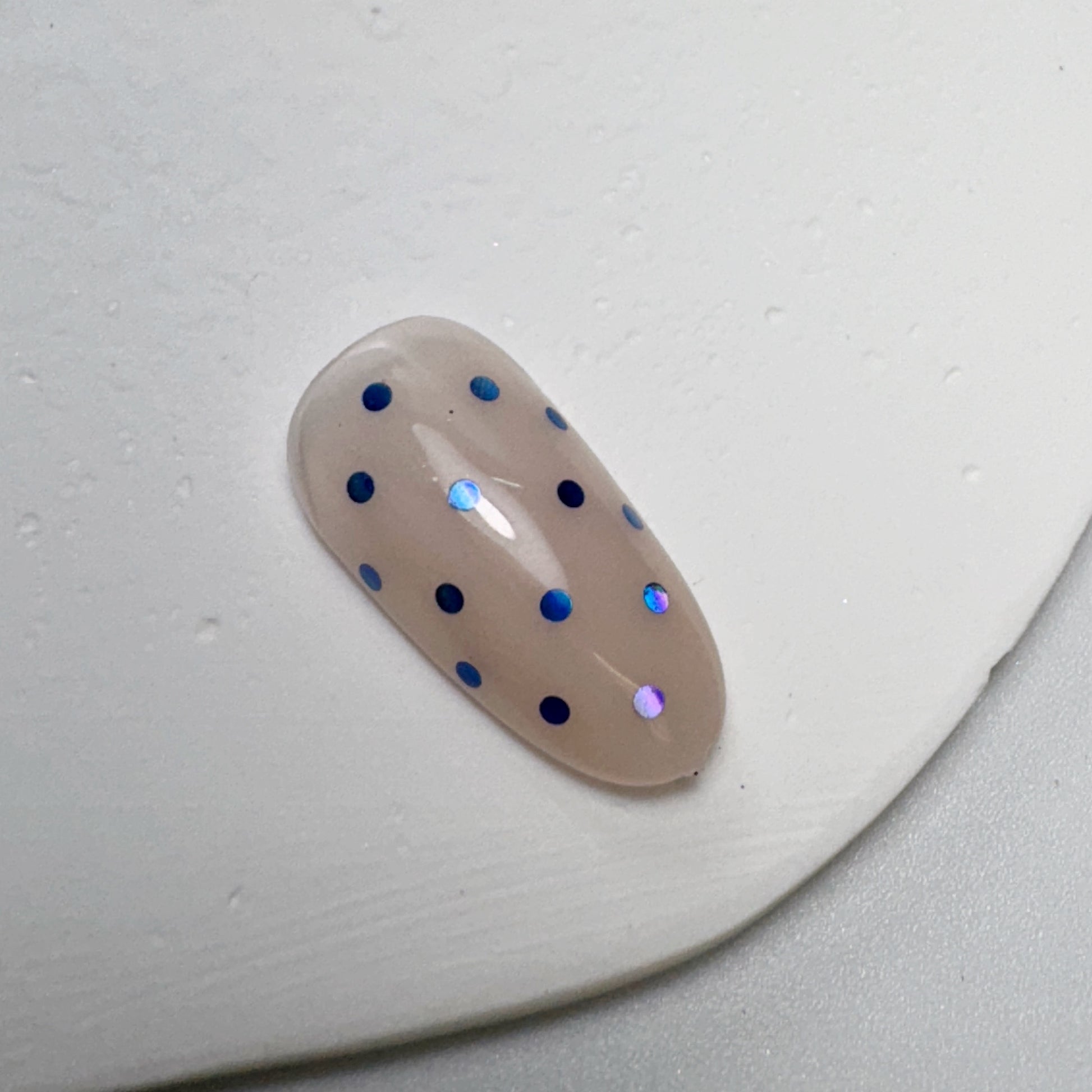 Decorated nail tip on white textured surface.