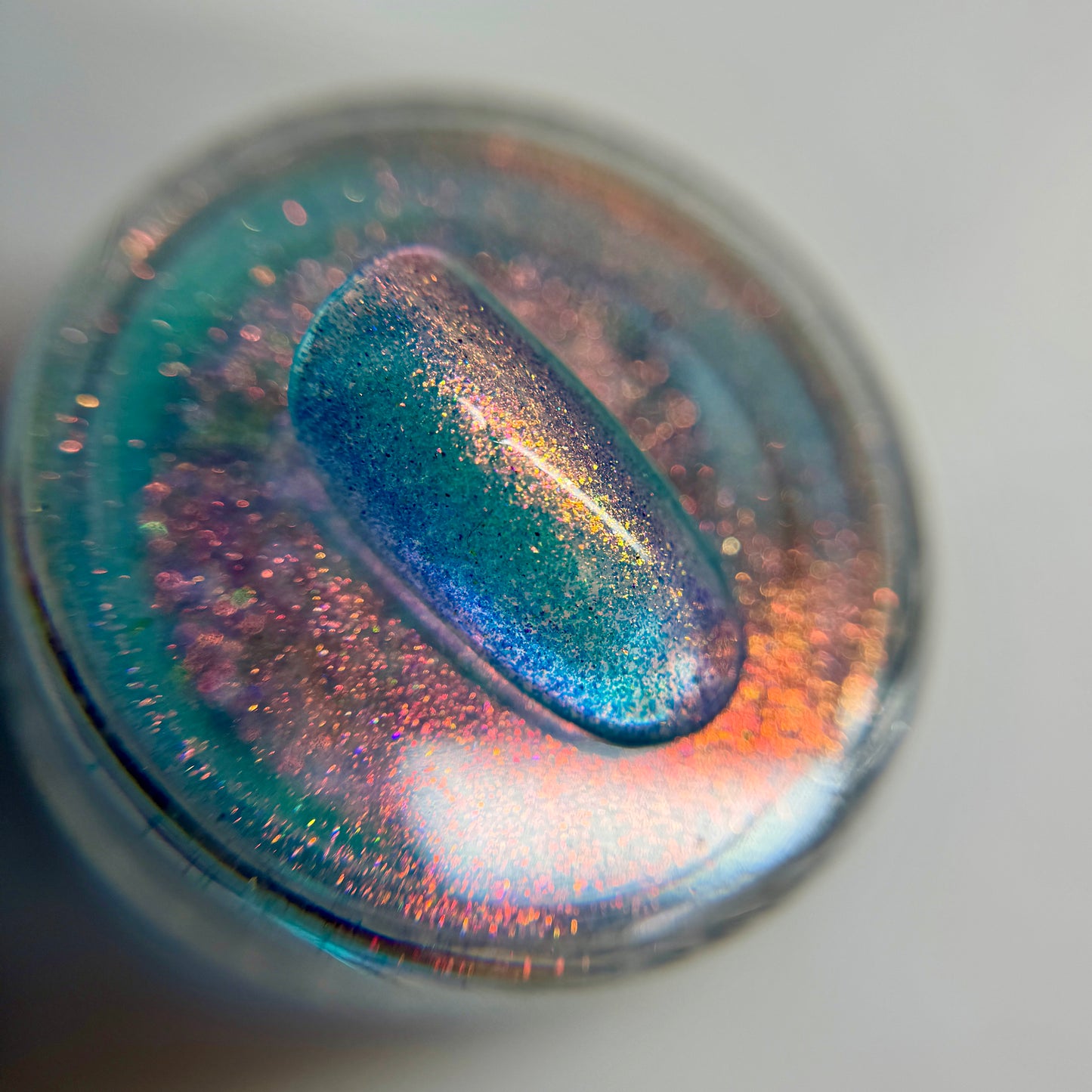 close up of iridescent colored bail tip resting on transparent jar on blurred background