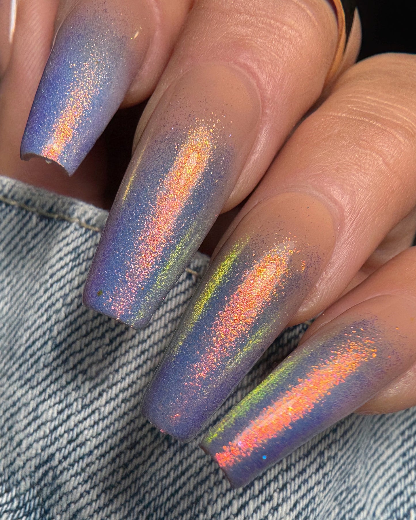 Nails with glittery gradient design on a denim background