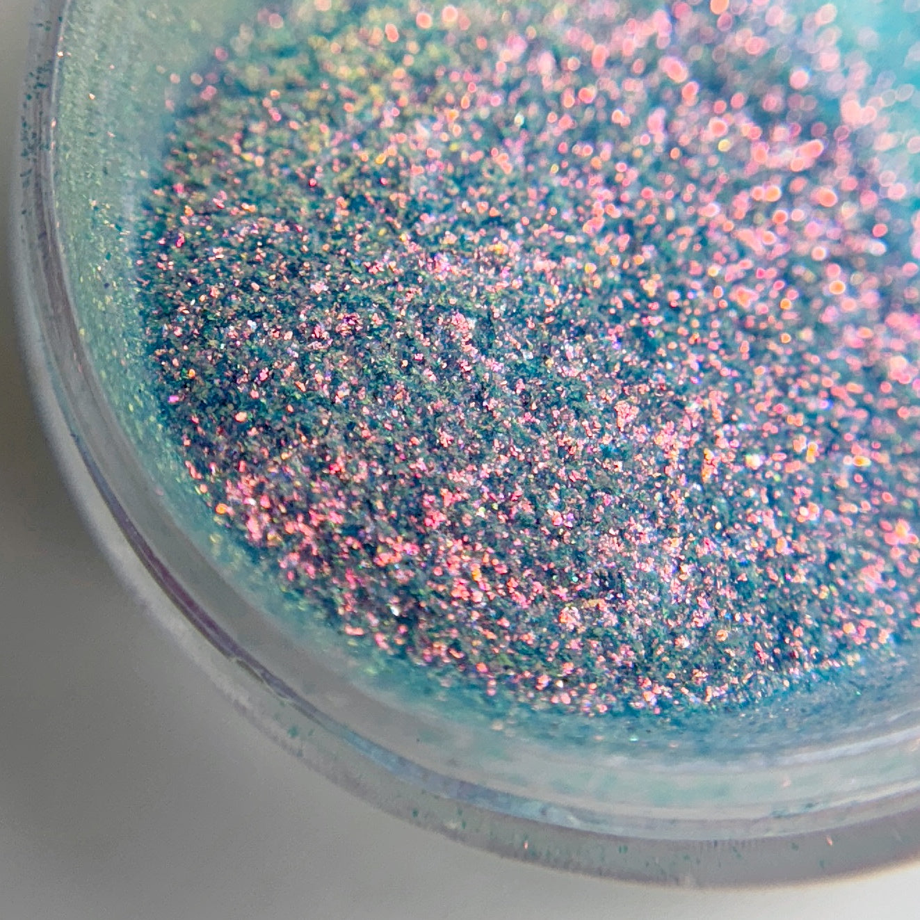 A close-up view of a jar containing blue fine glitter  in transparent jar.