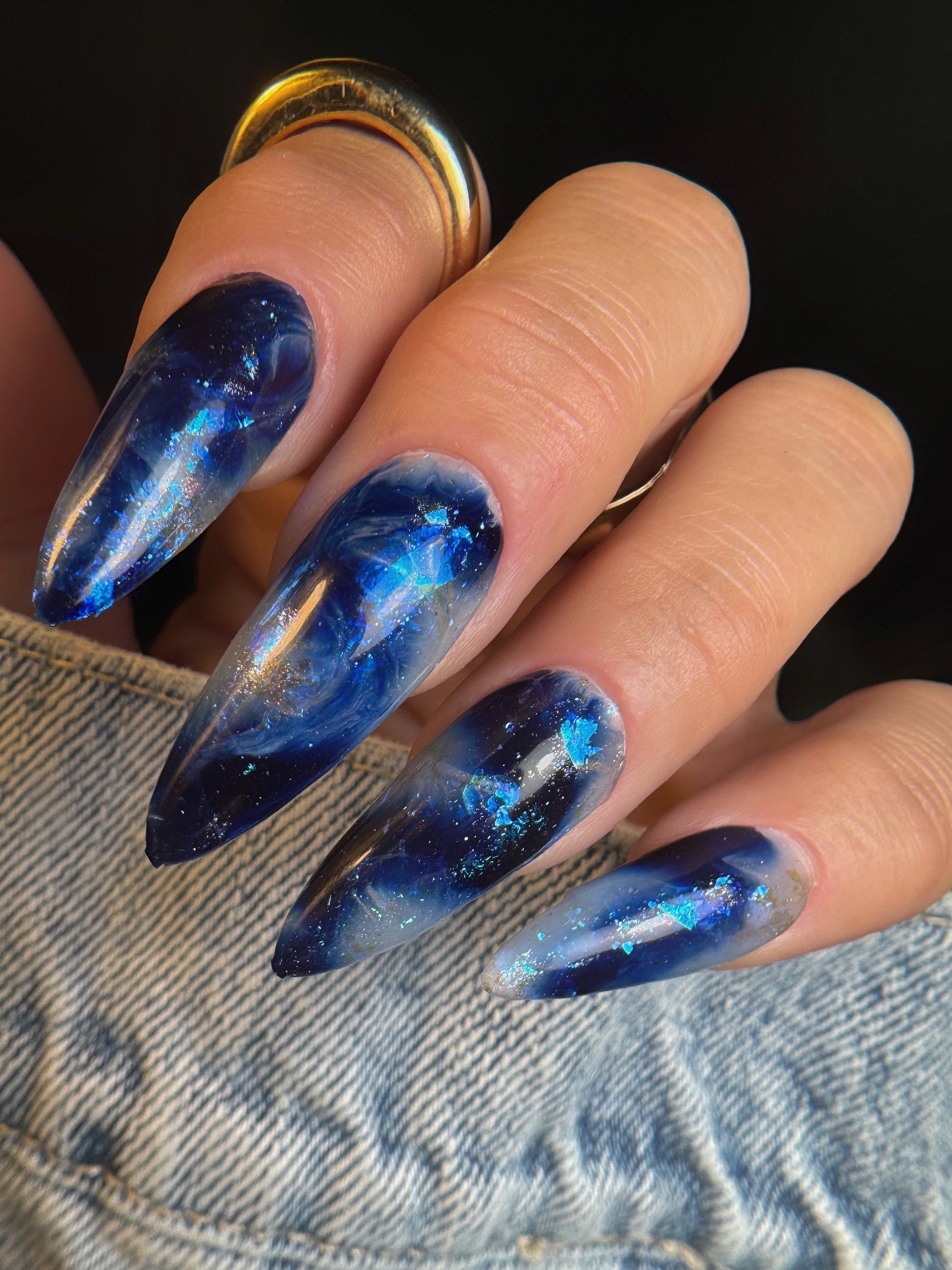 Nail art with blue marble nail art on a dark background