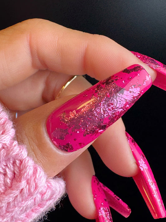 Close-up of a hand with pink glittery nails and a pink textured sleeve.