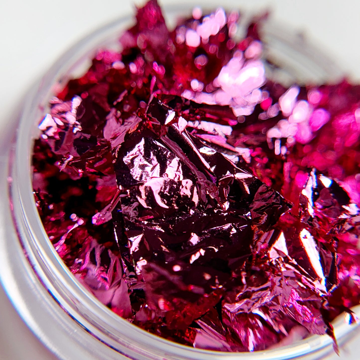 Close-up of nail foil in clear jar on blurred background.