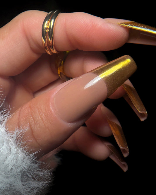 Close-up of a hand with a gold nail design on dark background