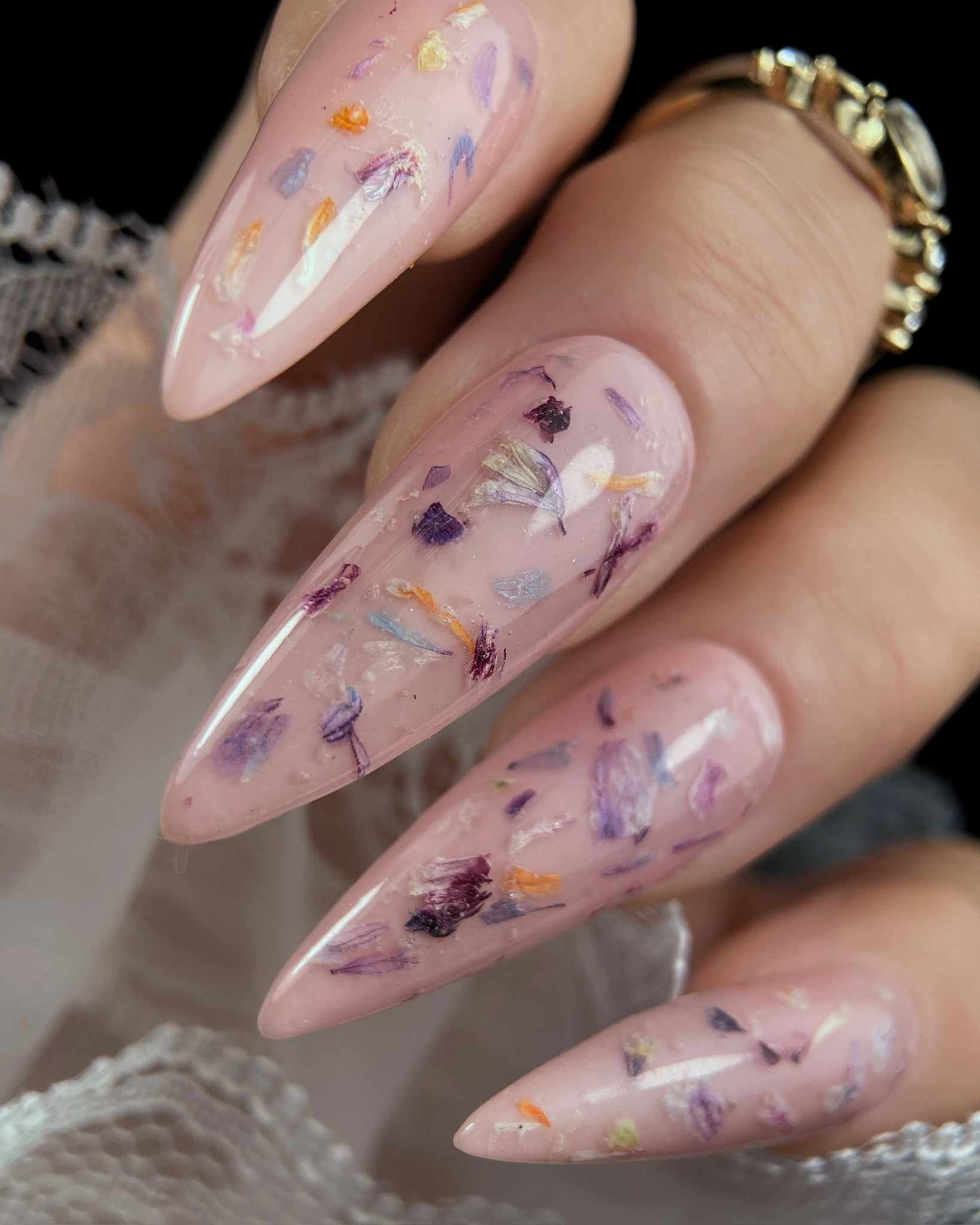 Almond-shaped nails with pink nail polish and floral decorations on a blurred background