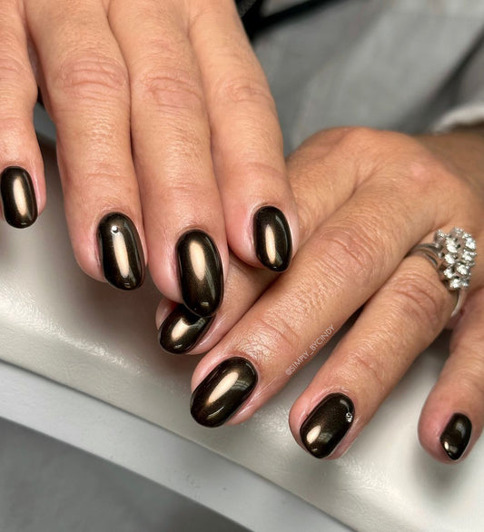 Close-up of hands with metallic nail color on a neutral background