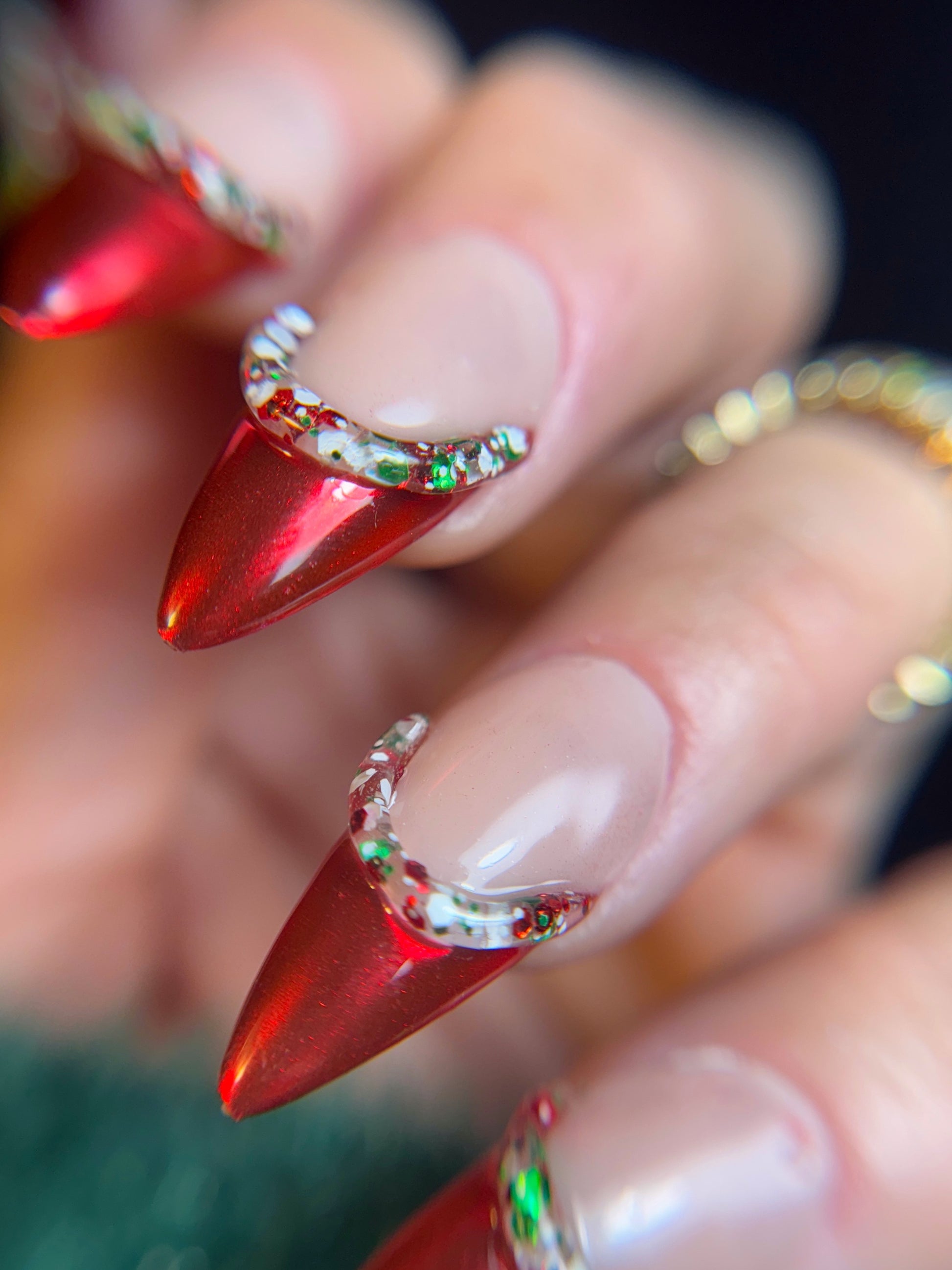 Close-up of red stiletto nails with decorative elements on a blurred background