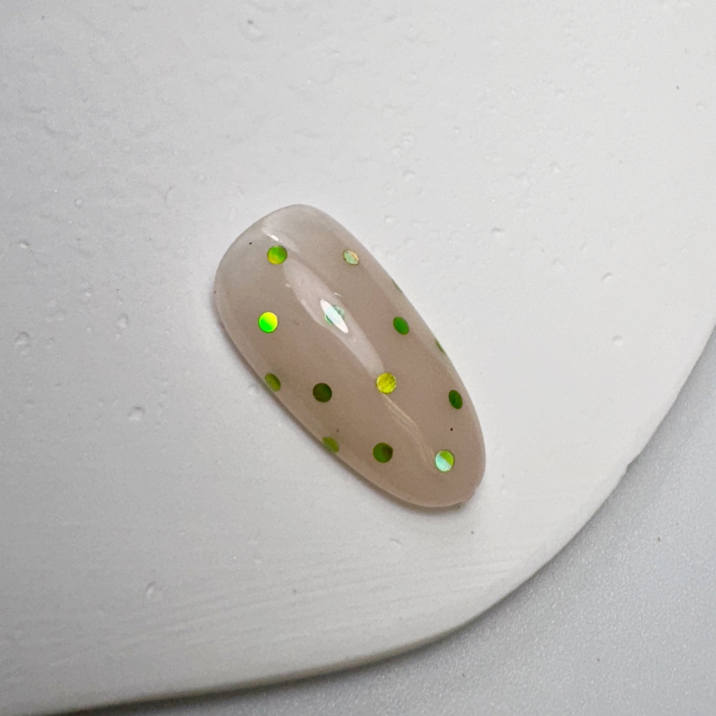 Decorated nail tip on white textured surface.