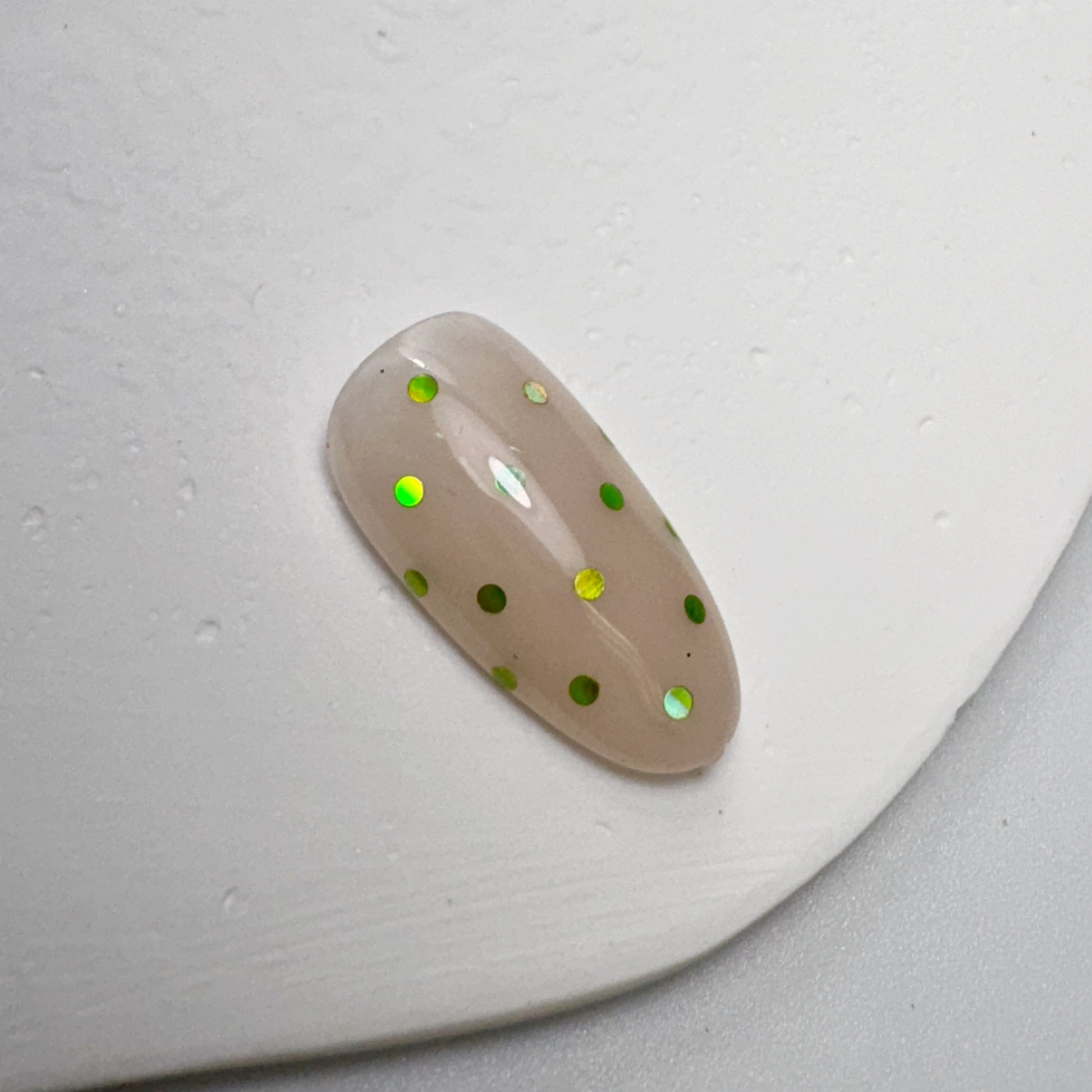 Decorated nail tip on white textured surface.