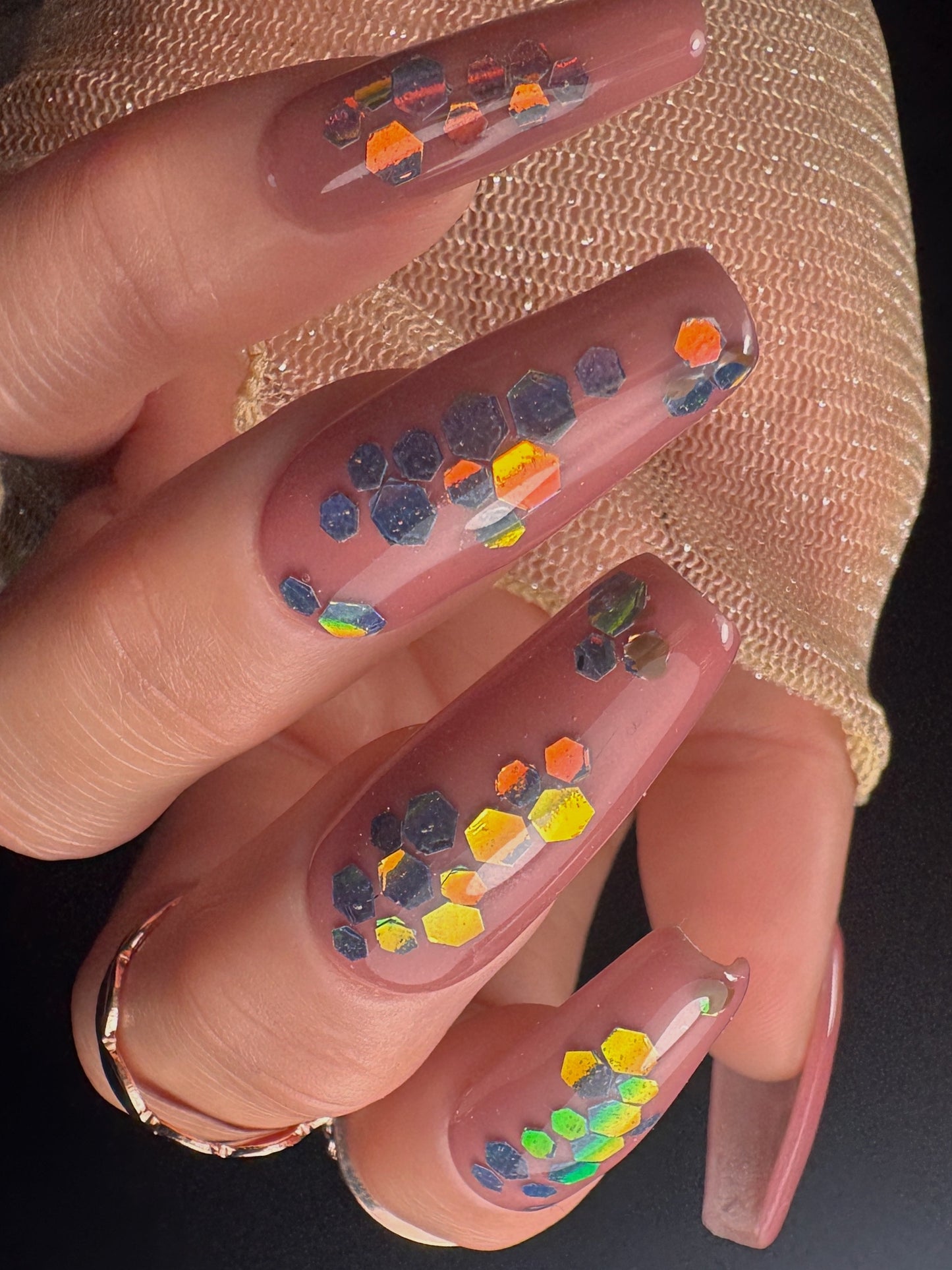 Nails with colorful hexagonal patterns on a textured surface