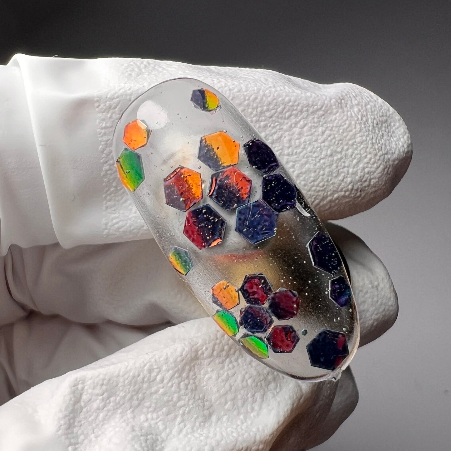 gloved hand holding decorated nail tip