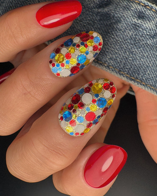 Nails with colorful glitter design and red polish on a denim background