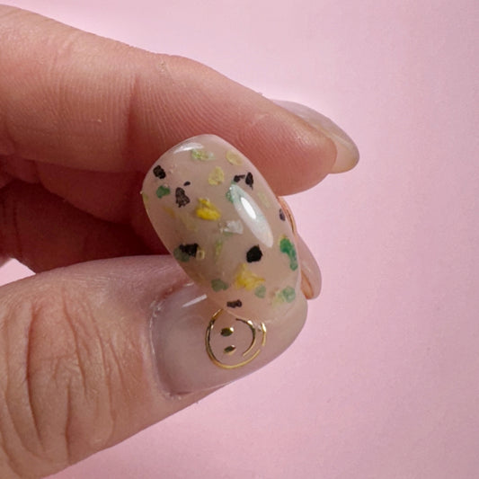 Close-up of a hand holding decorated nail tip on pink background 