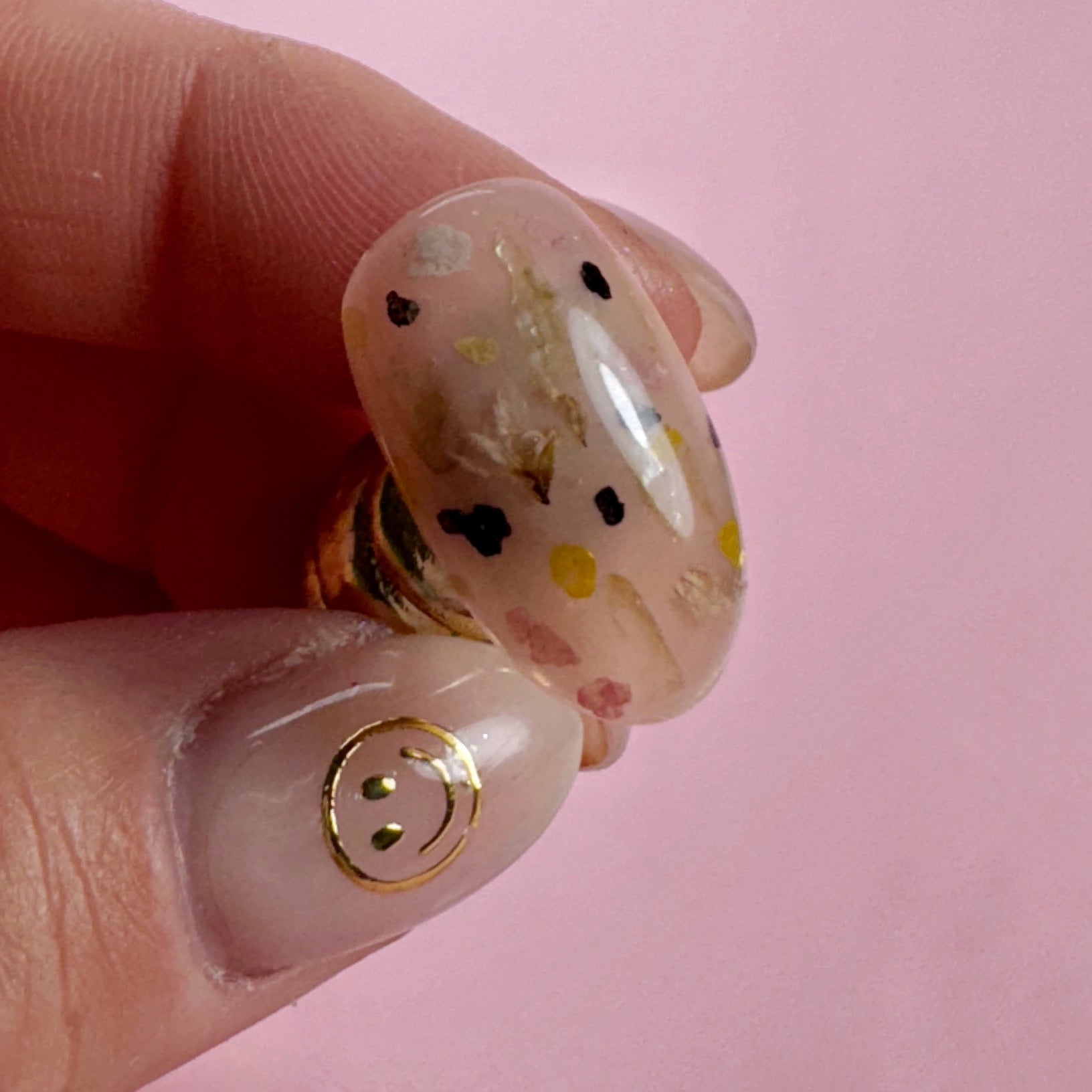 Close-up of a hand holding decorated nail tip on pink background 