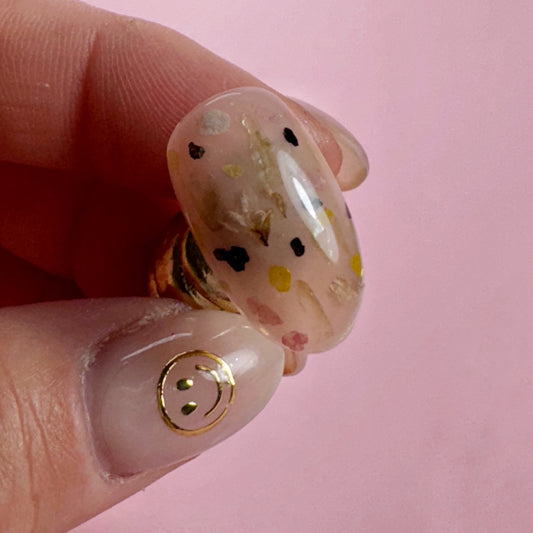 Close-up of a hand holding decorated nail tip on pink background 