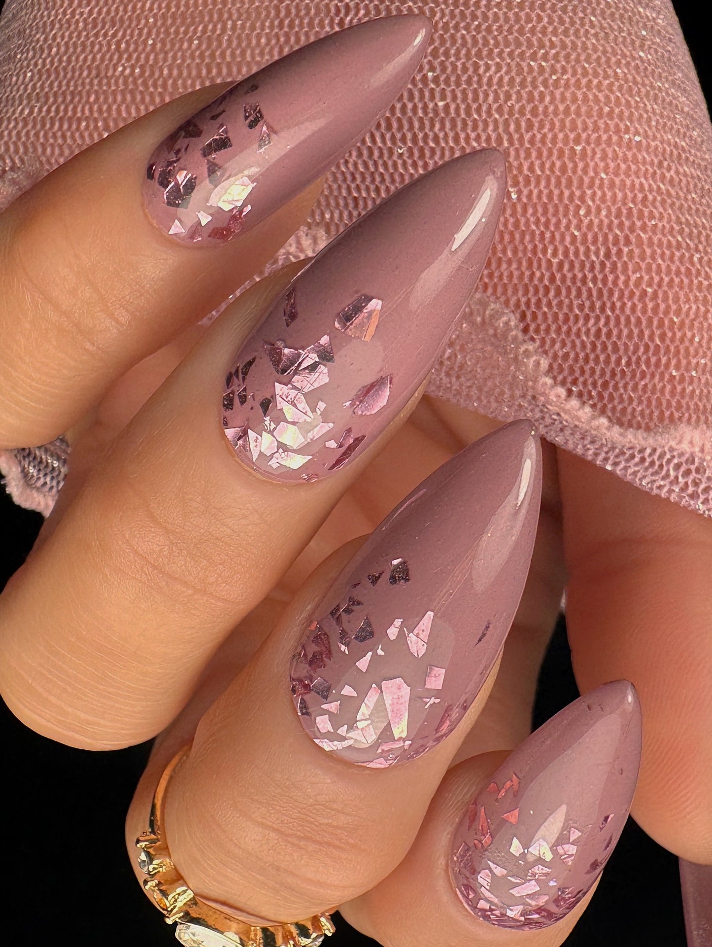 Pink glittery nail design on a hand with a blurred background