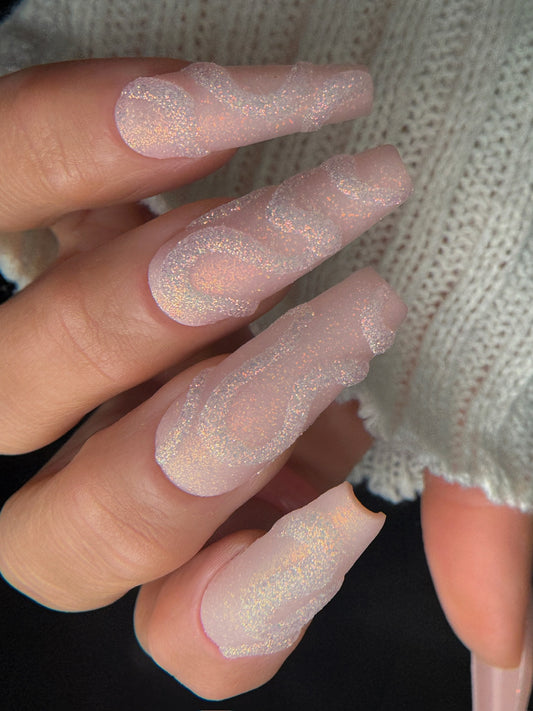 Close-up of a hand with pink glittery nails against a neutral background