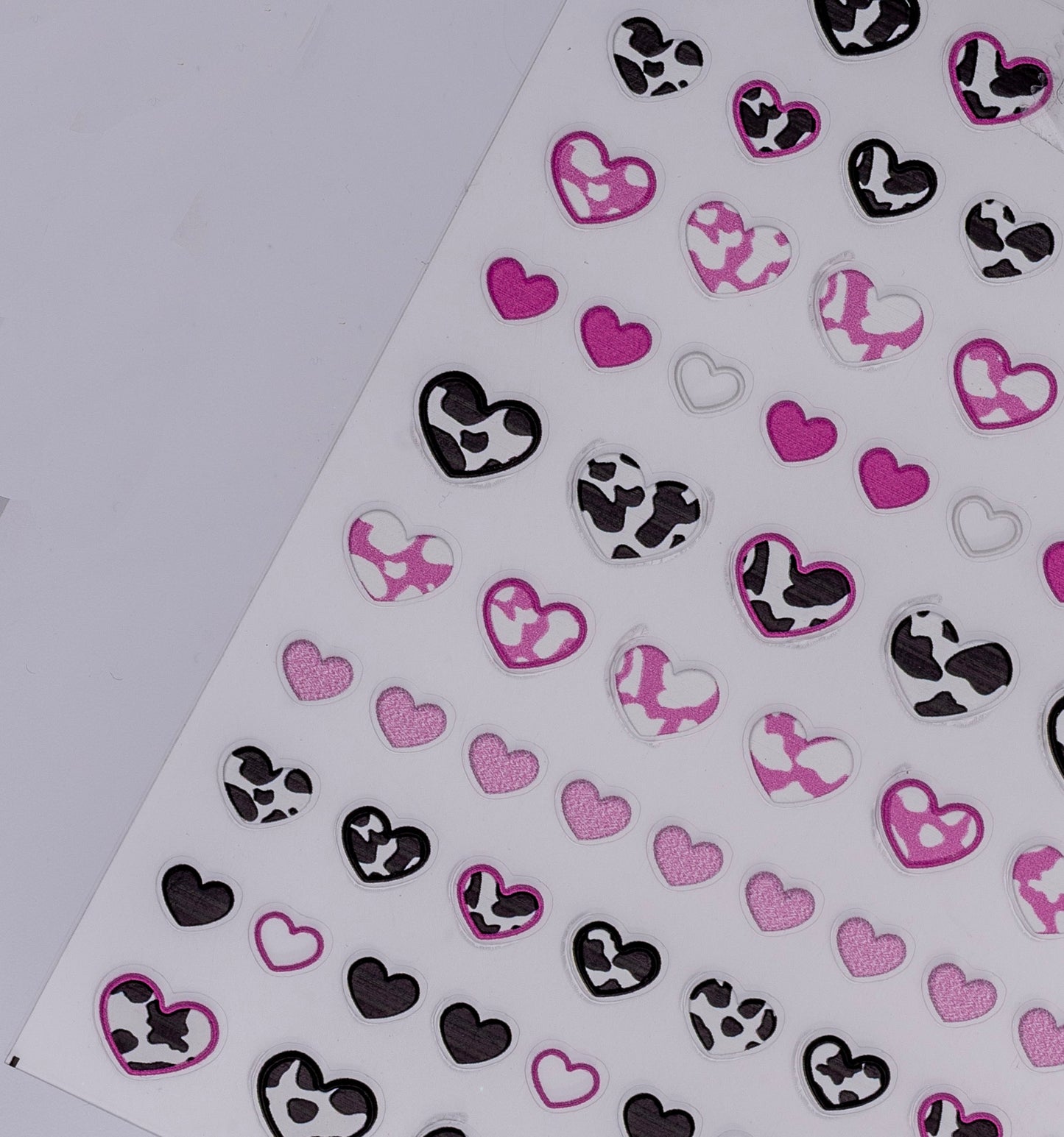 Heart-shaped stickers with black, white, and pink patterns on a white background