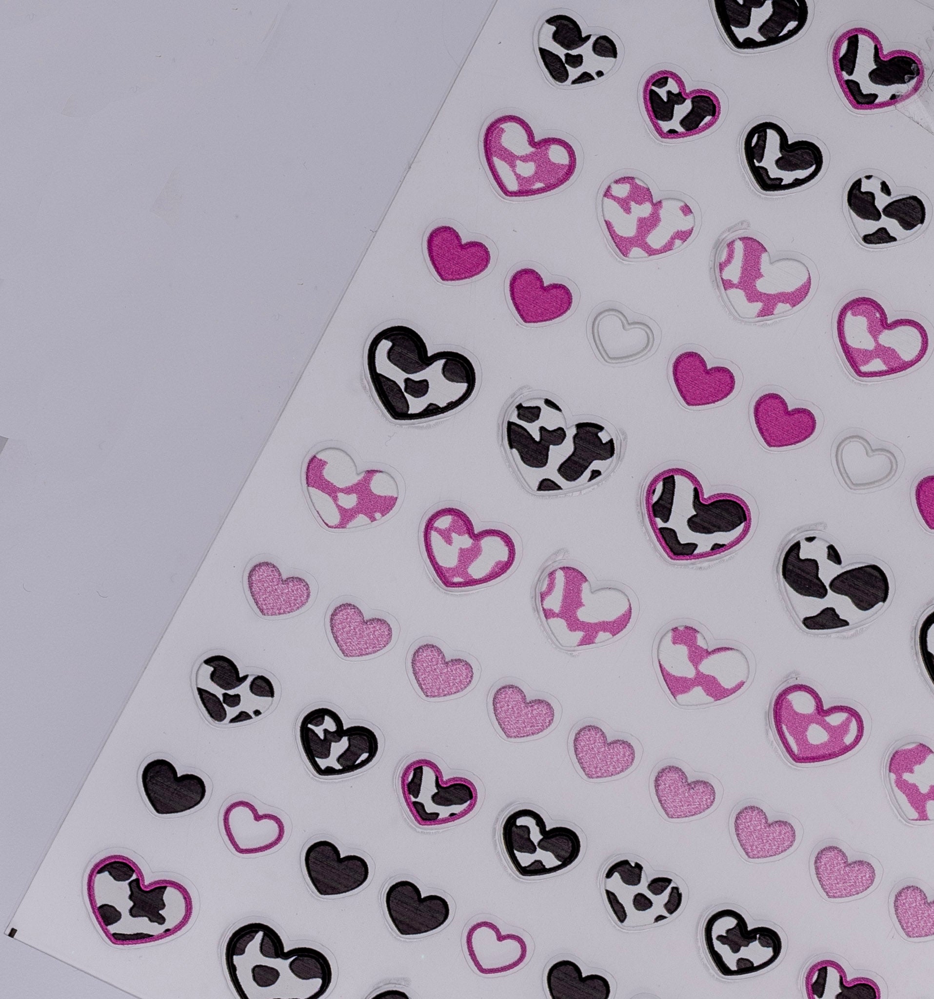 Heart-shaped stickers with black, white, and pink patterns on a white background