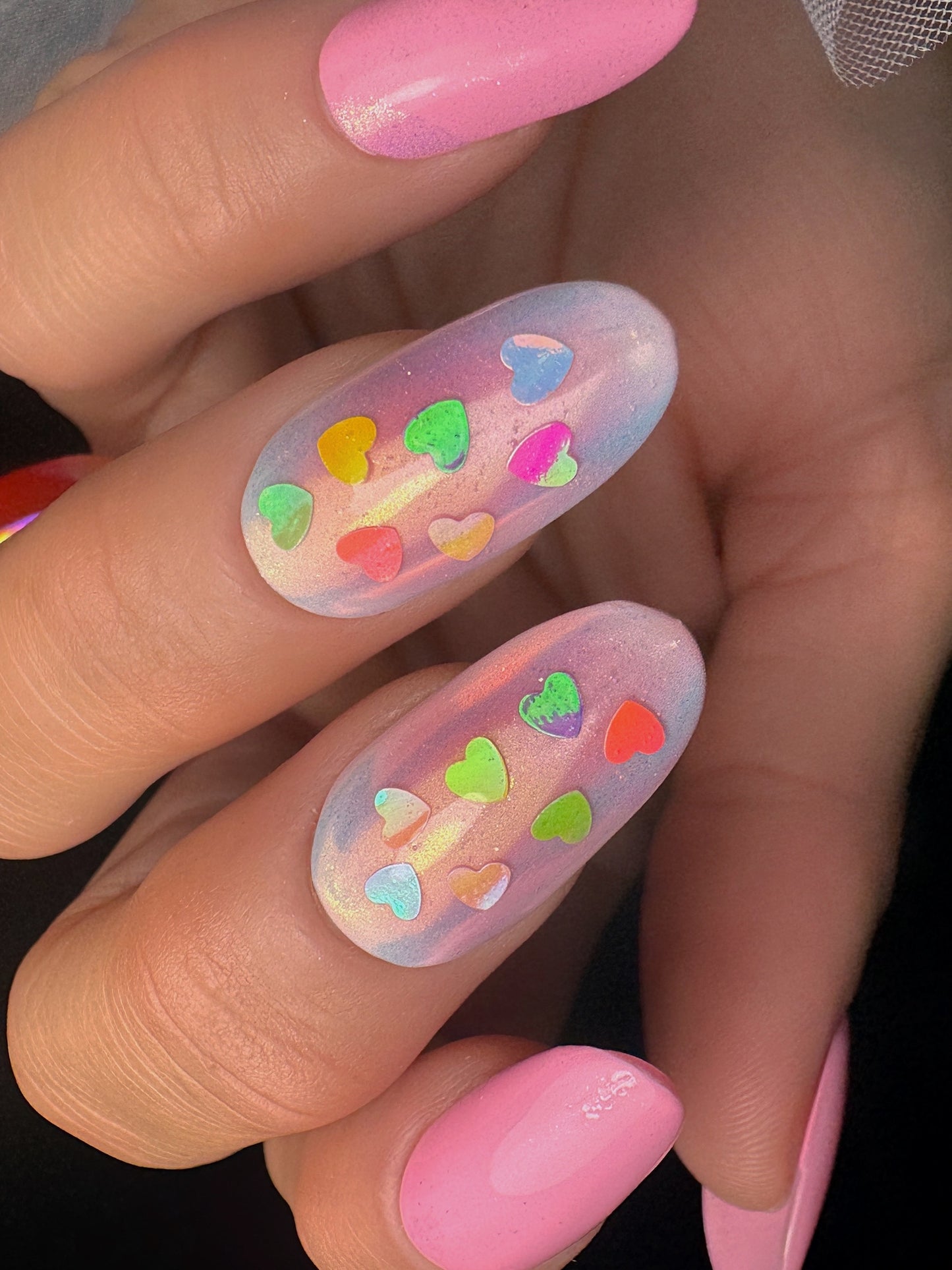 Nails with colorful heart designs and pink polish