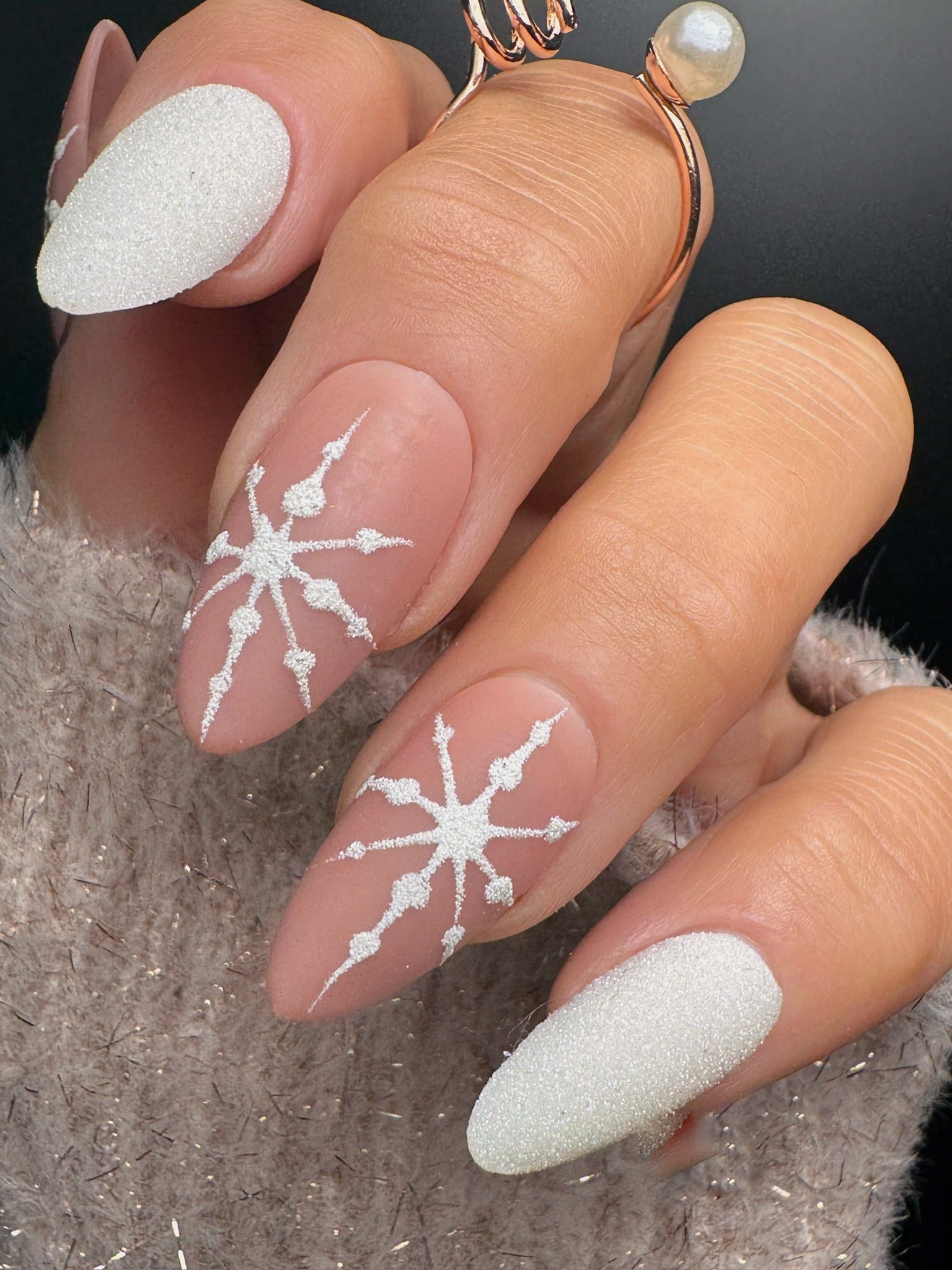 Nails with white snowflake designs on a neutral background