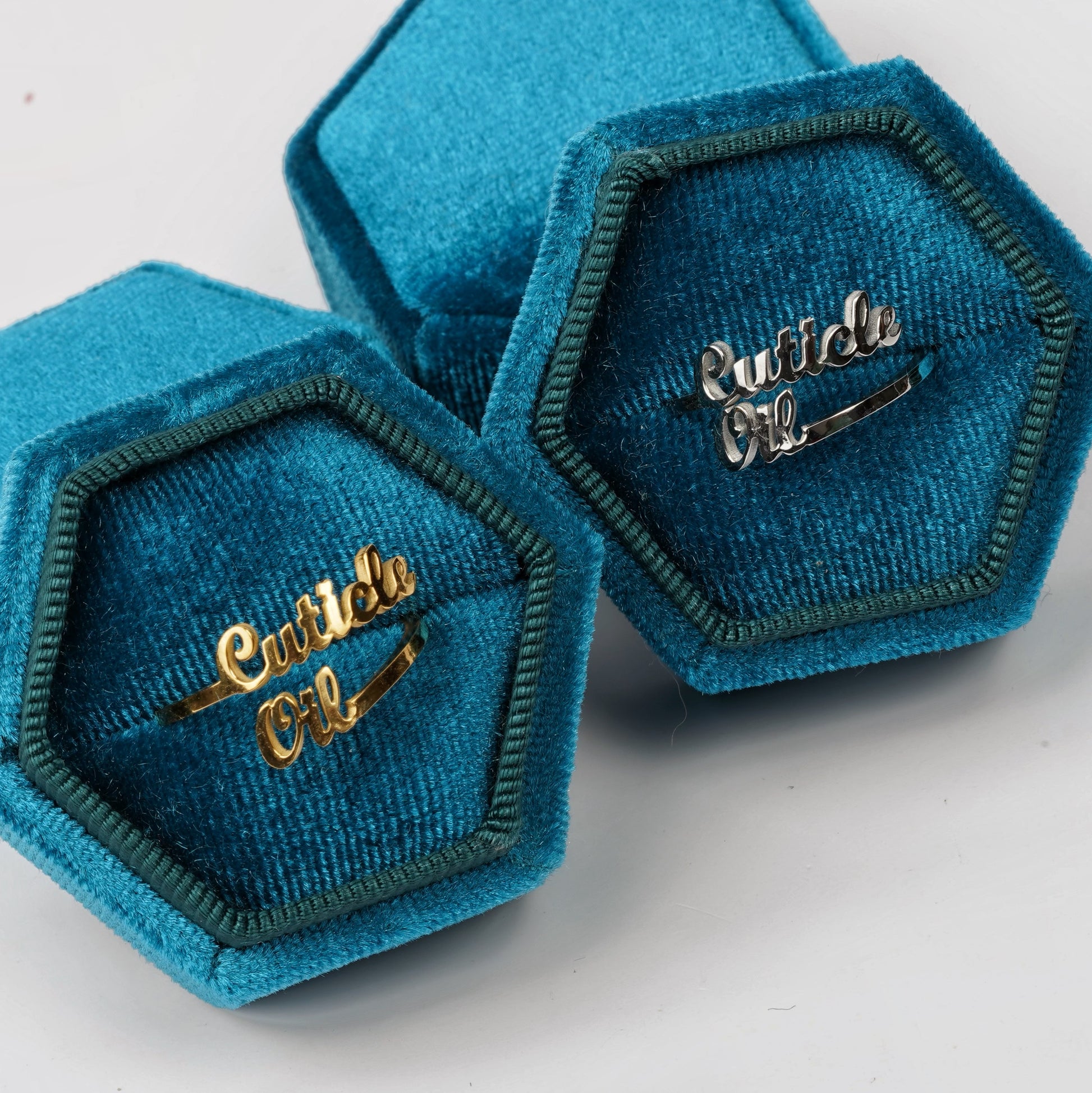 Two blue ringboxes with gold and silver rings staggered on white background. 