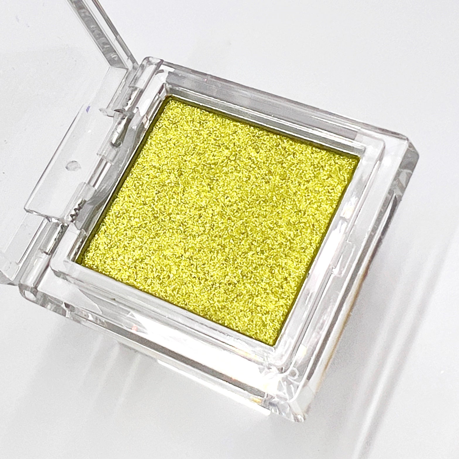Clear compact with metallic pressed chrome powder on white background.
