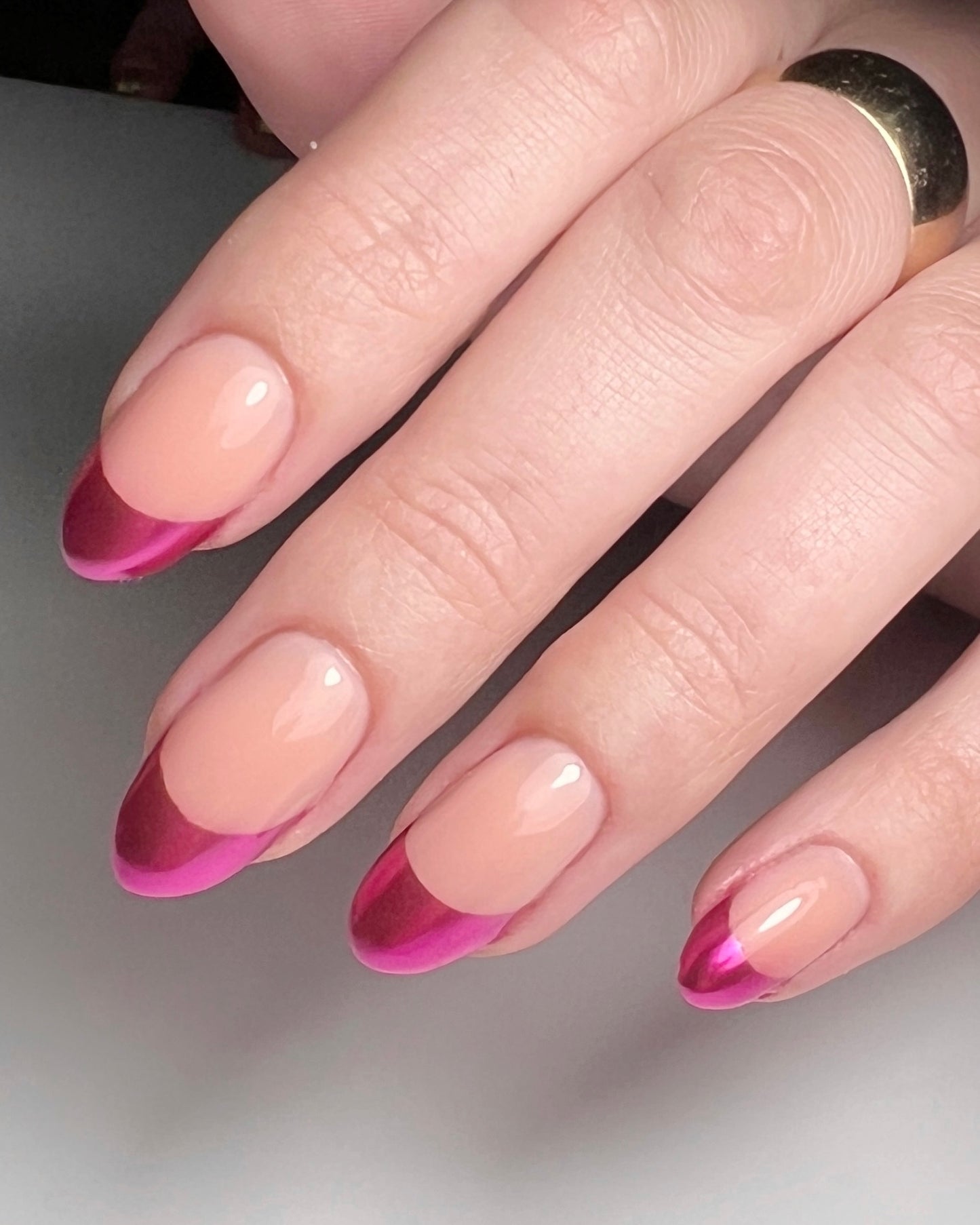 Close-up of a hand with pink nail design on a neutral background