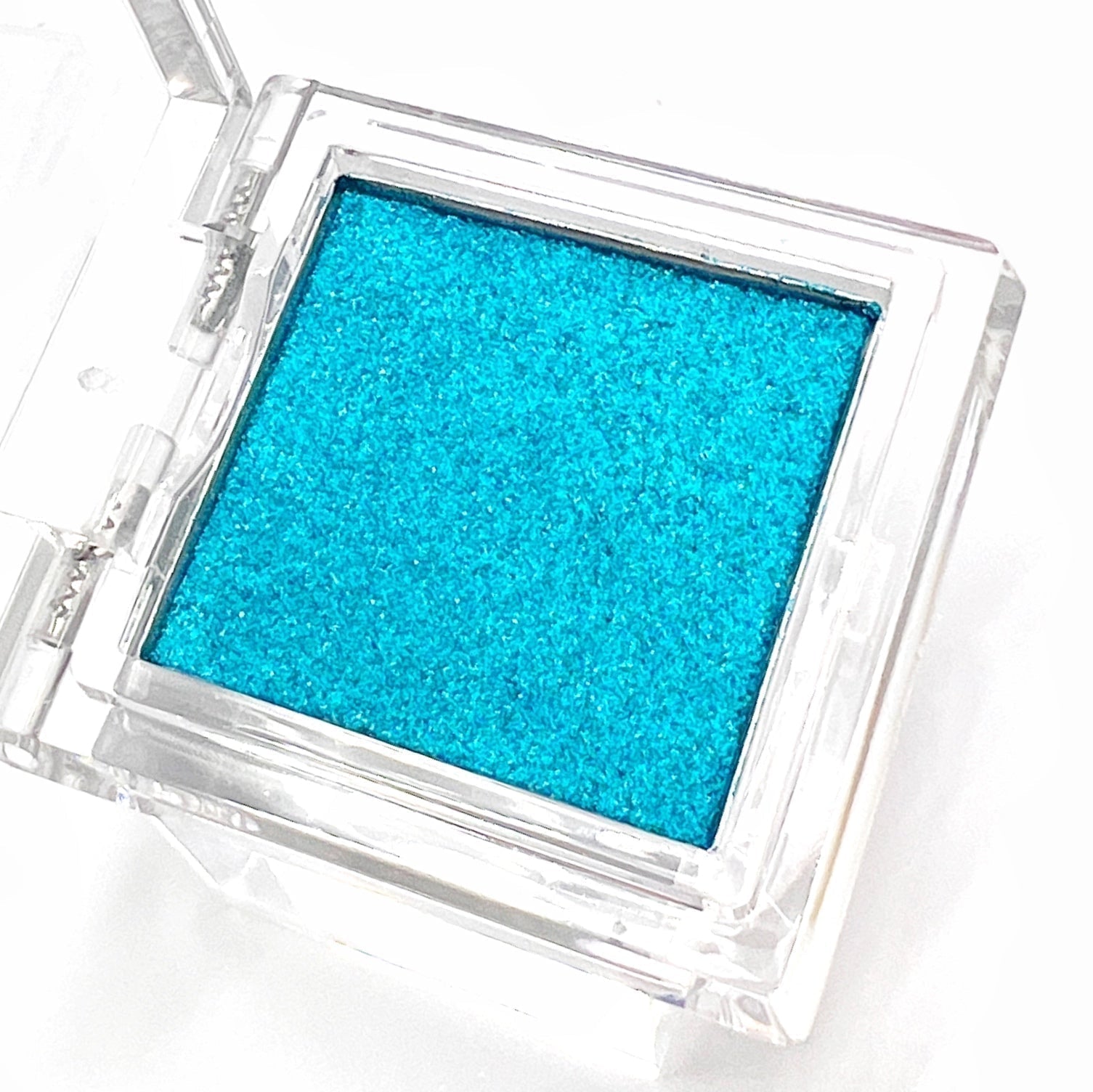 Detail view of  compact with metallic powder on white background. 