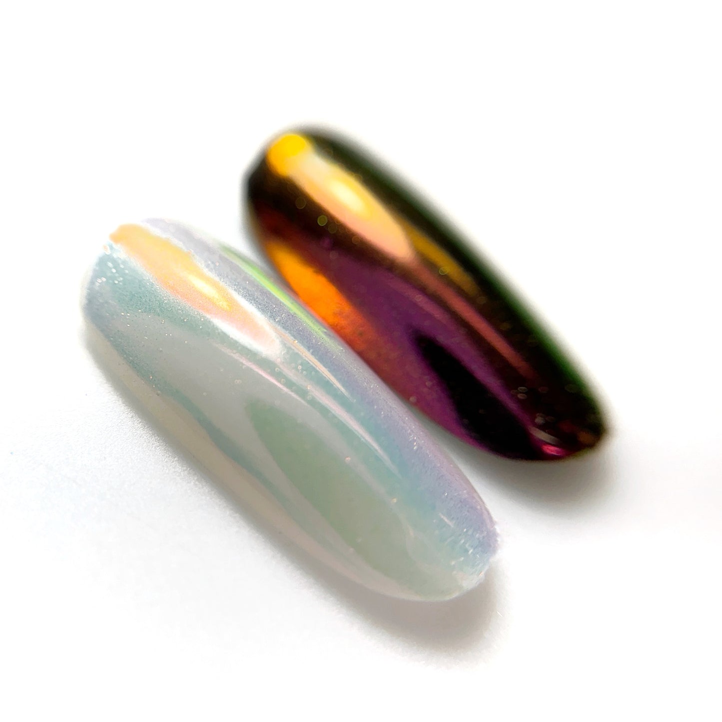 Metallic nail tips on white surface with blurred background.