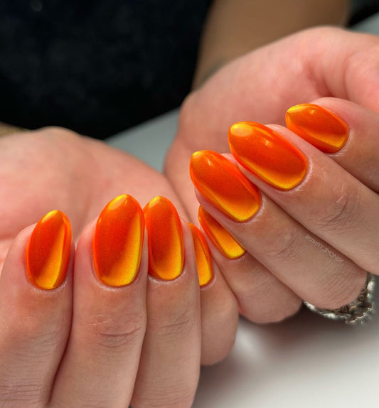Close-up of hands with orange and yellow gradient nail design on a neutral background