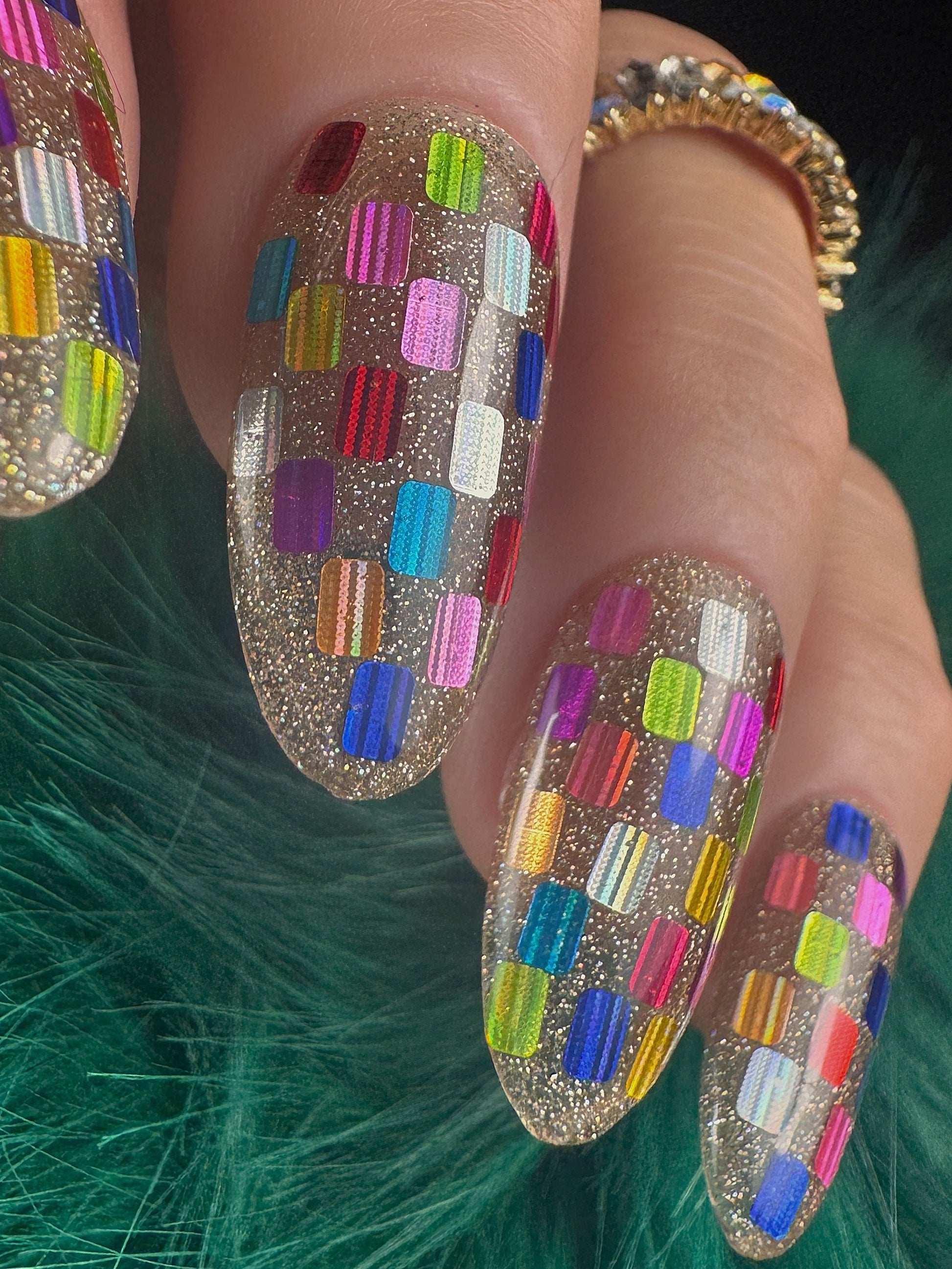 Nails with colorful geometric design on a green textured background
