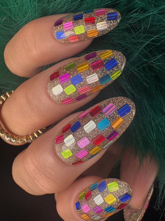 Nails with colorful checkered design on a green textured background