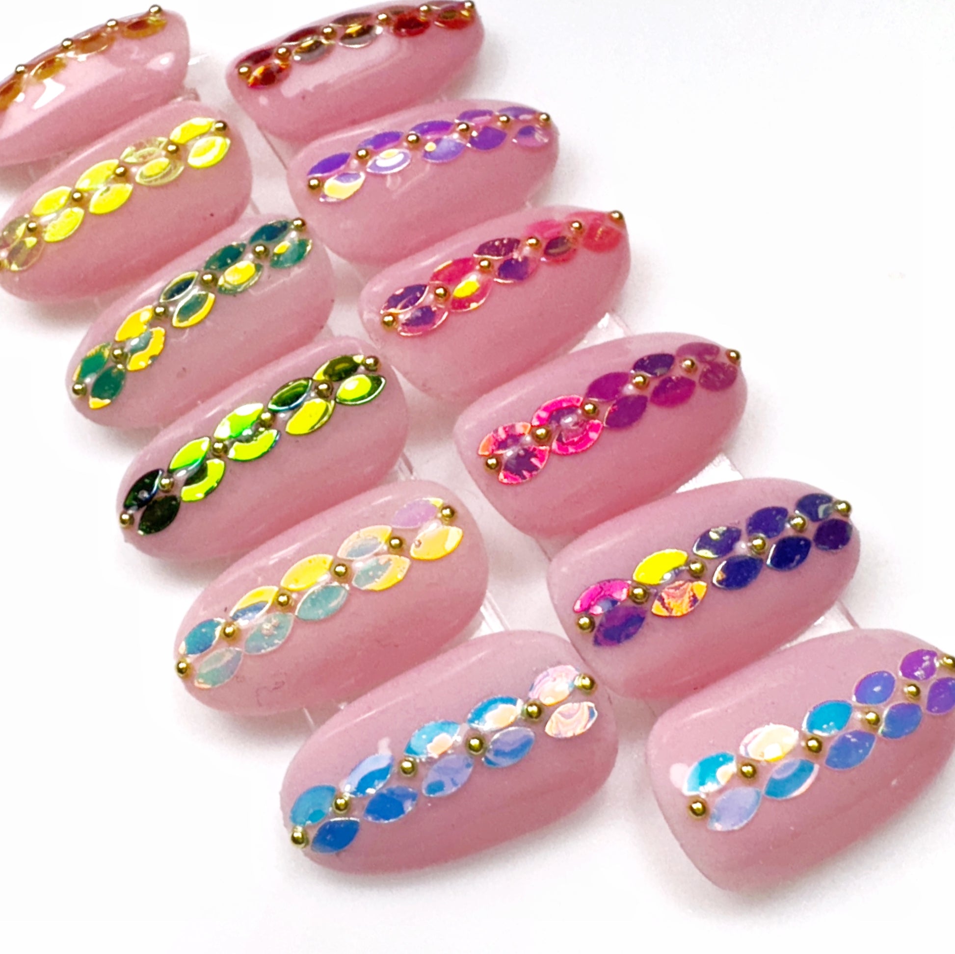 Pink nail art designs with colorful sequins on a white background