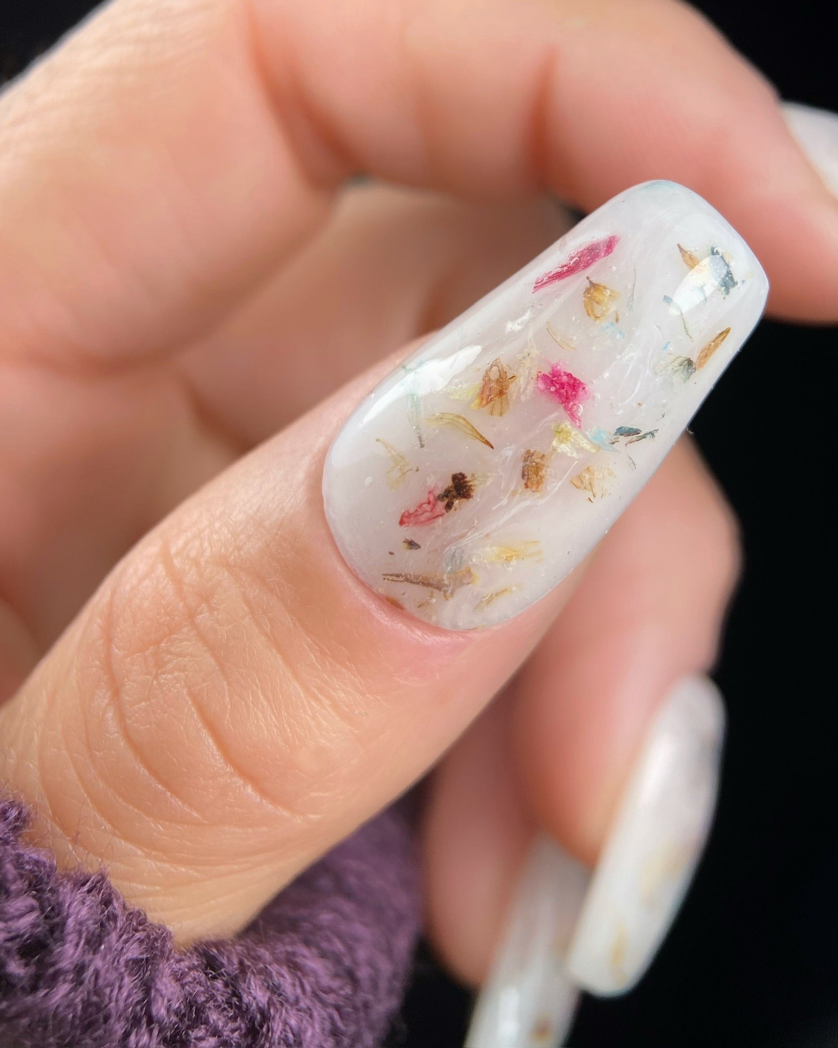 Close-up of a hand with a floral design on nails.
