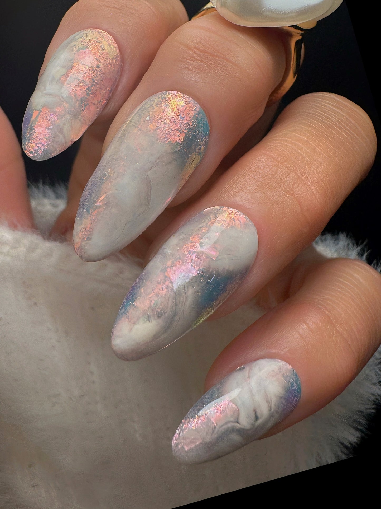 Nails with a marble design and glittery finish on a dark background