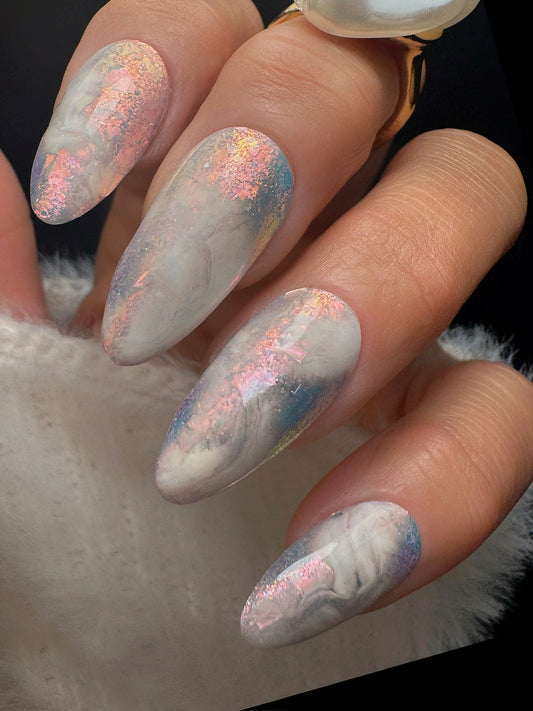 Nails with a marble design and glittery finish on a dark background