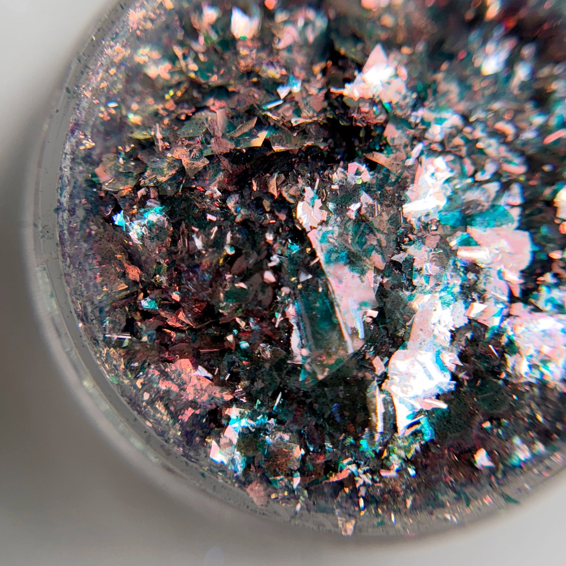 A close-up view of multicolored electric comet flakes in clear jar on blurred background.