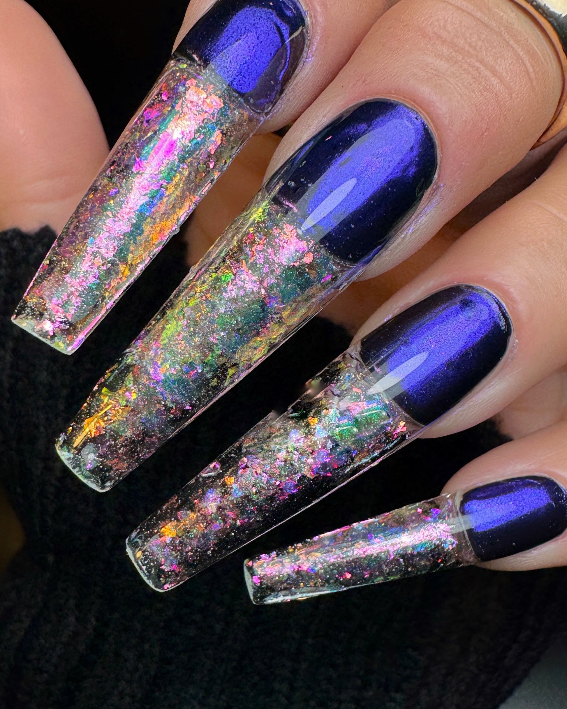 Nails with blue polish and multicolored glitter on a black background