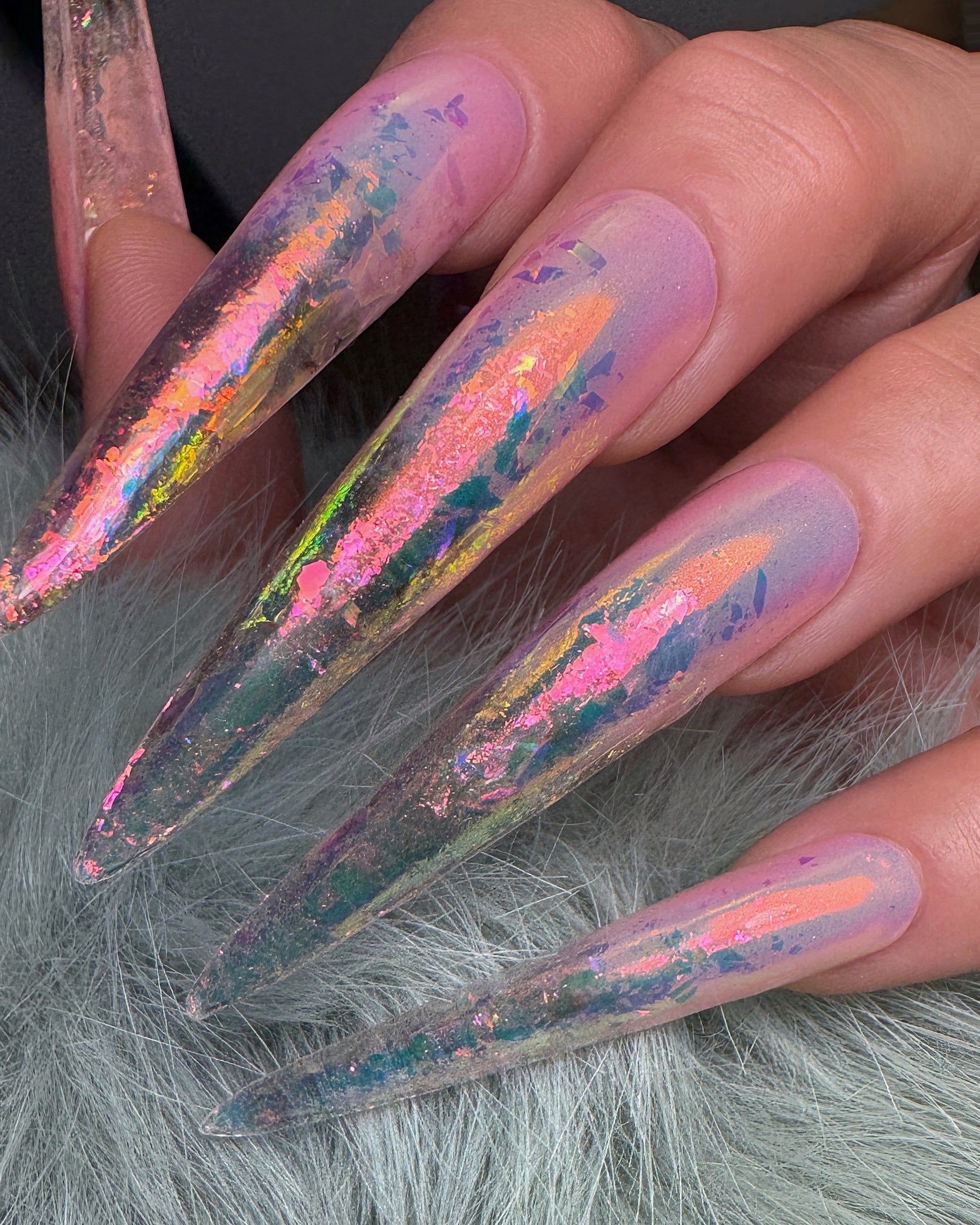 Nails with iridescent glitter design on a gray fur background