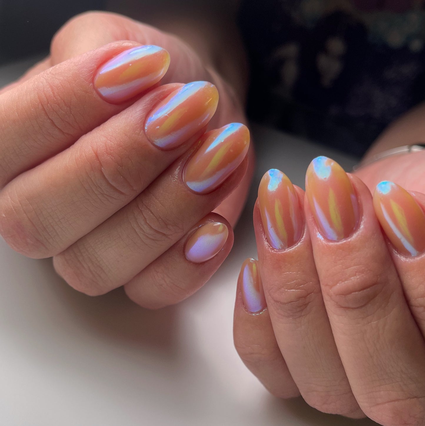 Manicured hands with metallic nails on light background.