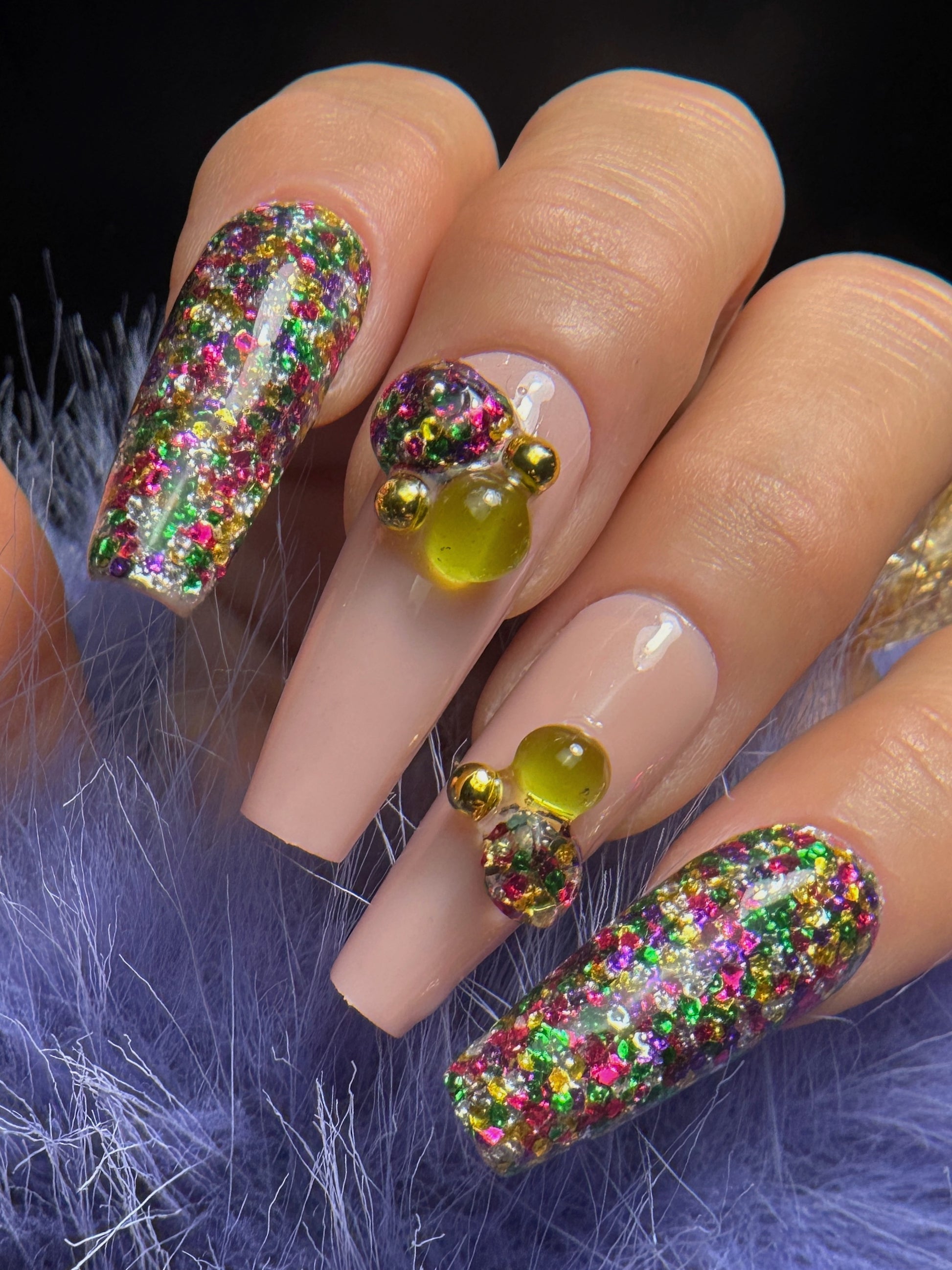 Nails with colorful glitter design on a purple fur background