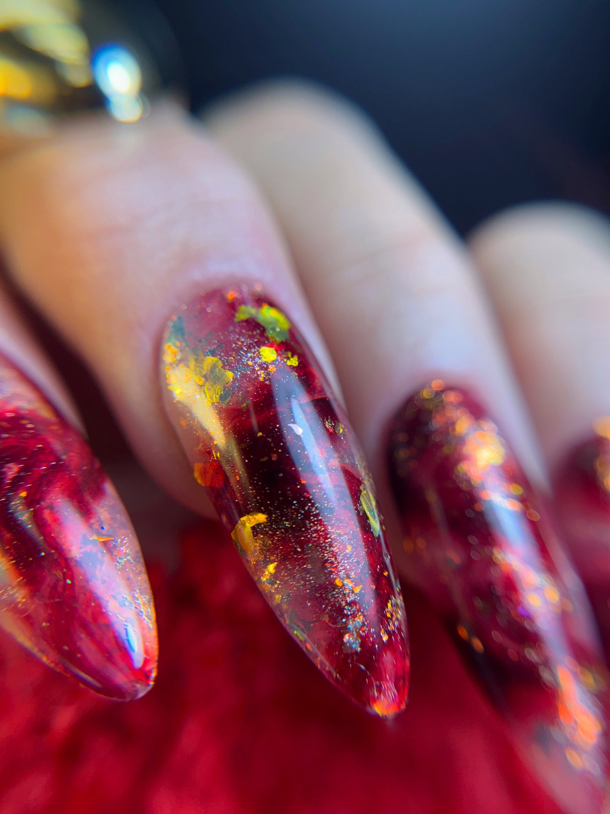 Close-up of a hand with red nail design on a blurred background