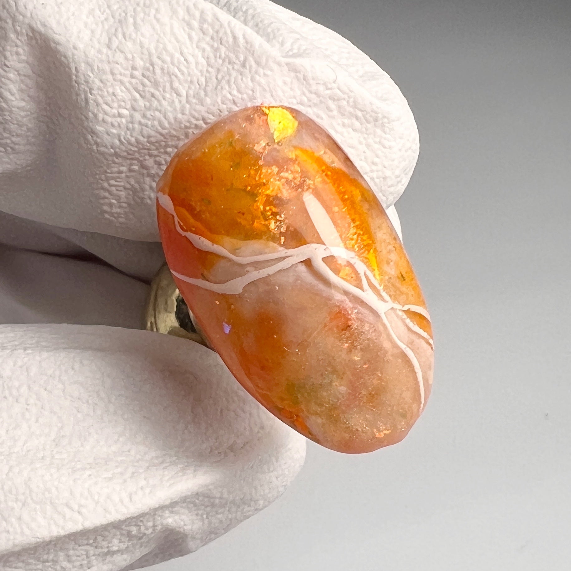 Hand in white glove holding a decorated nail tip on blurred background