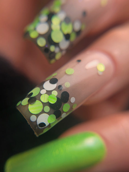 Close-up of a hand with green nail polish and a patterned nail design.